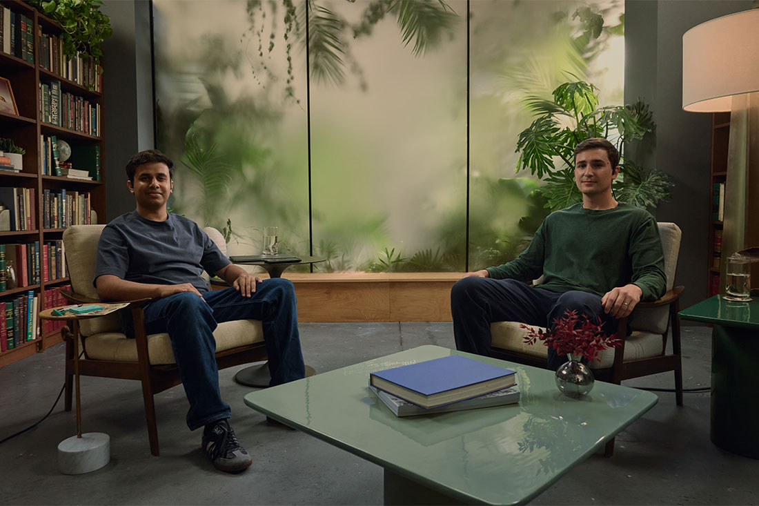 two men sitting in chairs with AI wearable headset