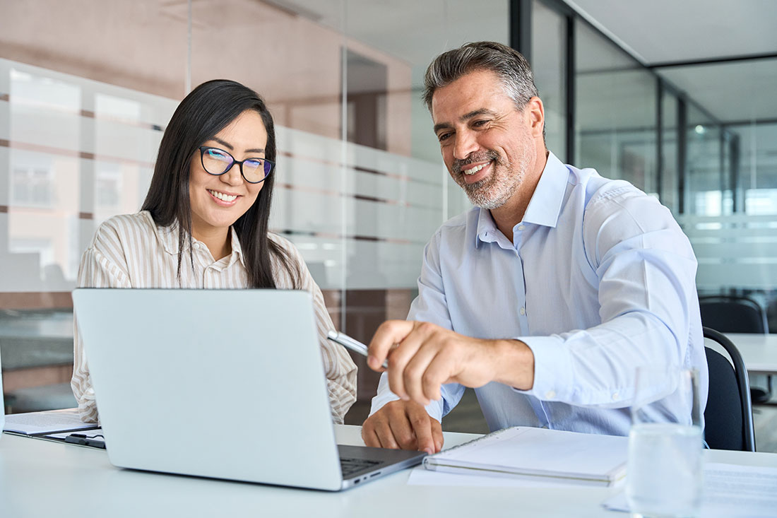 manager mentor teaching female worker looking at laptop discussing strategy