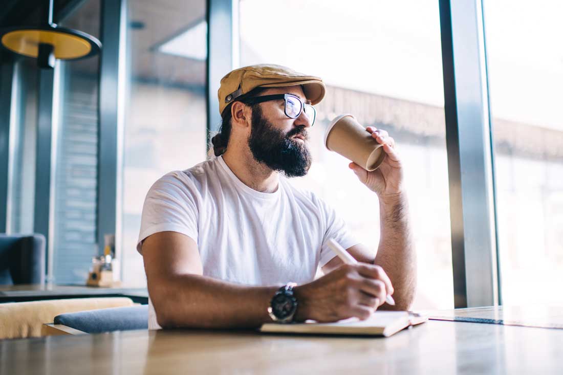 man writing in a cafe