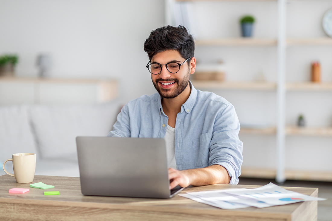 A male freelancer smiles and works on his laptop