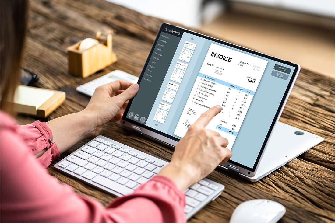 woman with long-sleeve pink shirt pointing to tablet with an invoice on the screen