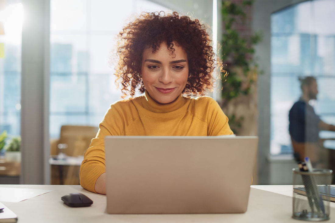 Woman with curly hair using laptop in modern office