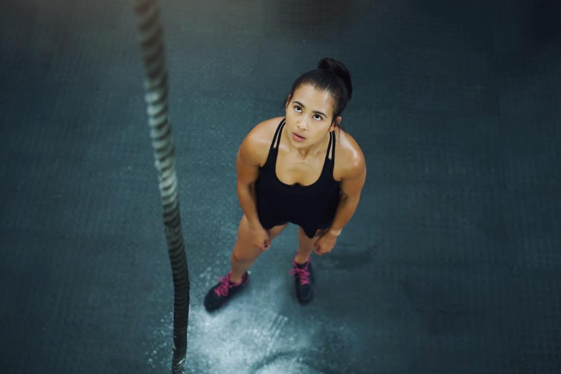 Young women looks up at rope to climb. Resilience quotes