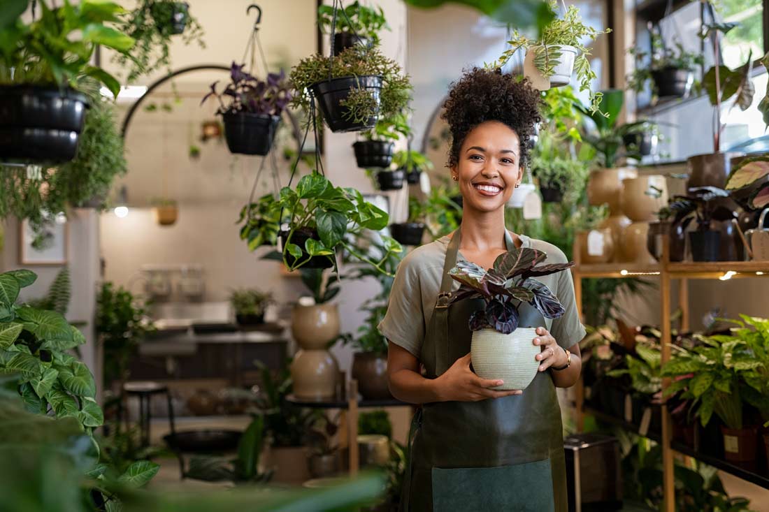 Smiling small business owner holding a plant